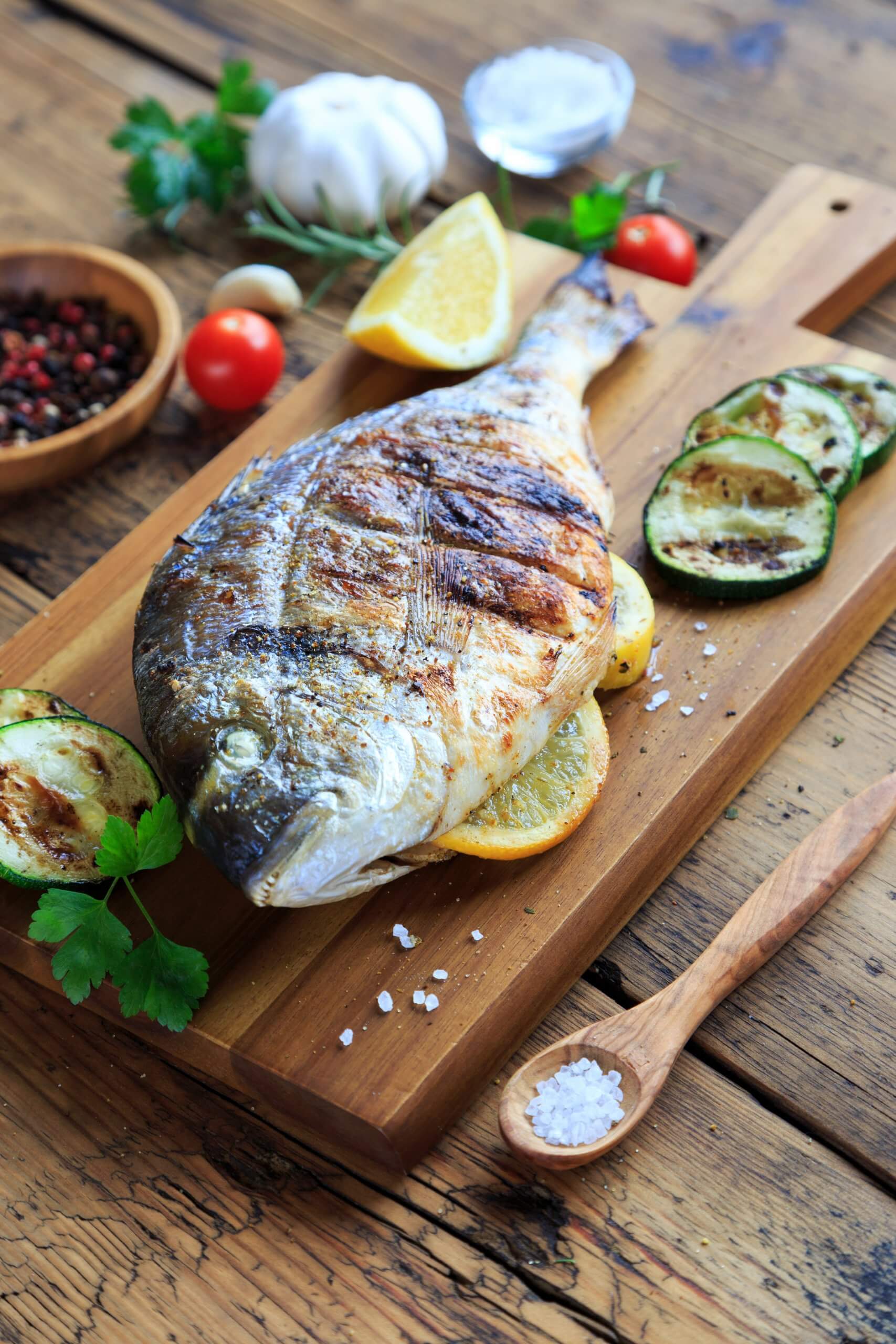 grilled sea bream on wooden board with vegetables